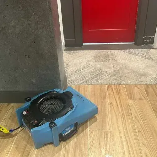 An air mover drying wood-look tile beside an open doorway