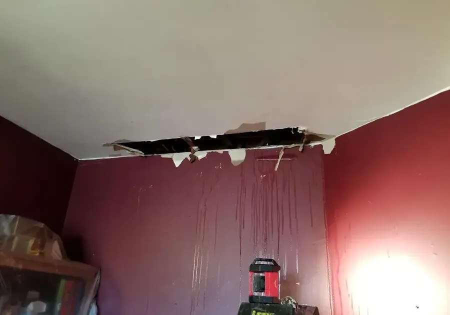 Collapsed ceiling drywall with water streaks running down a bedroom wall